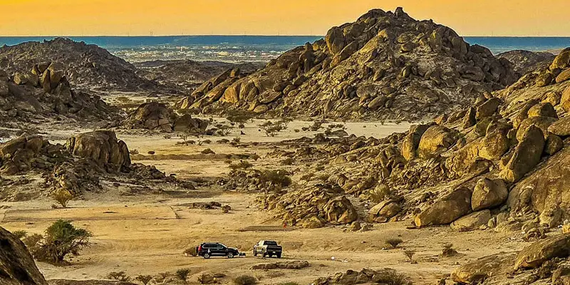 Panoramic high-angle view of 4x4 vehicles parked in the rugged rocky valley terrain of Moon Valley near Jeddah.