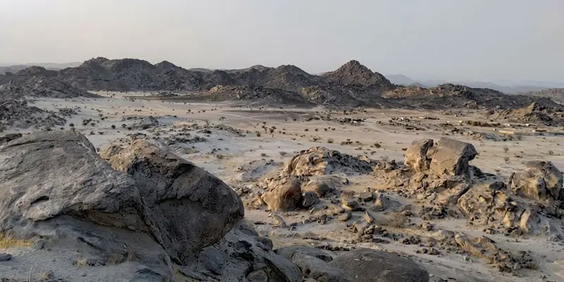 Vast landscape view of unique dark rock formations and desert plains at Moon Valley near Jeddah.