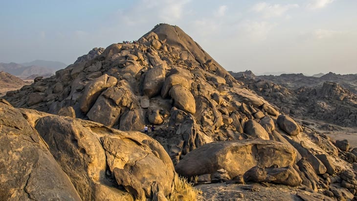 Hikers climbing the rocky peak of New Moon Valley during a desert tour from Jeddah